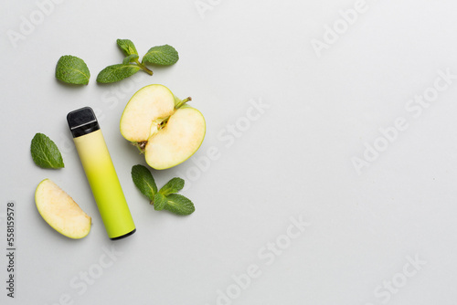 Disposable electronic cigarettes with fruits on color background, top view