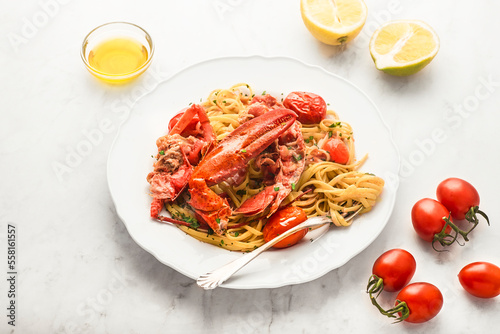 Lobster linguine pasta with ingredients for cooking. Lemon, tomatoes, olive oil, parsley on the white marble table. Delicatessen, rare seafood pasta recipe. Sardinia, Sicilian, Neapolitan cuisine.