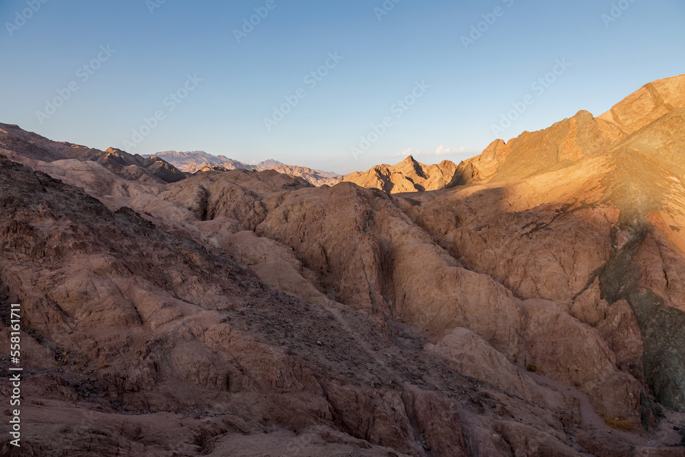 Beautiful stone mountains in the desert. Yellow sand on the mountains. Evening nature. Sunny summer day.