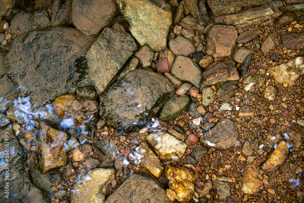 Background of clear river water with mossy rocks at the bottom.