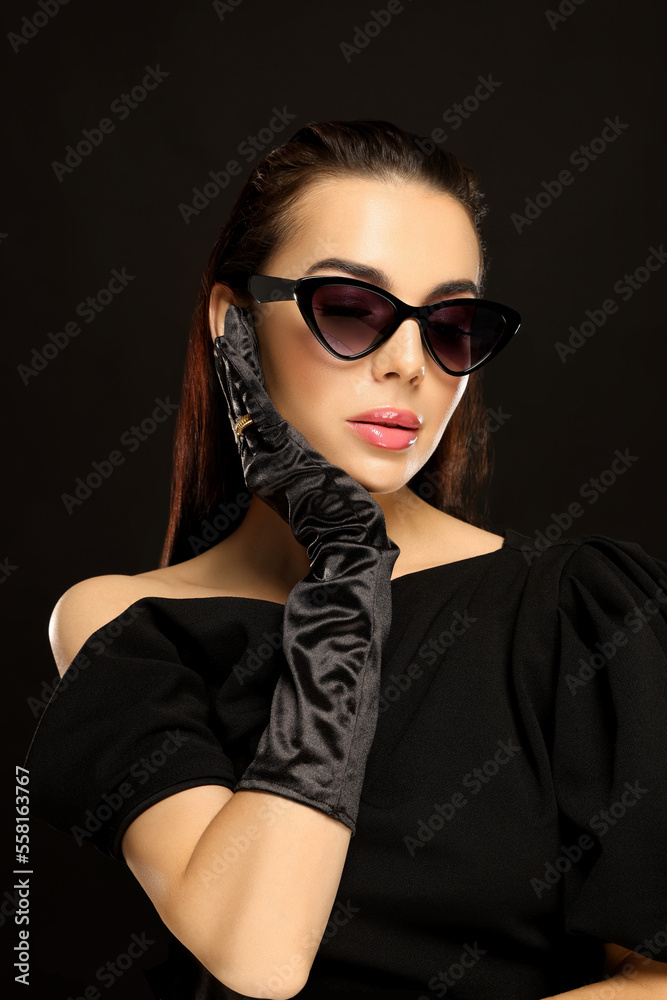 Portrait of beautiful young woman in sunglasses and elegant evening gloves on black background Portrait of beautiful young woman in sunglasses and elegant evening gloves on black background