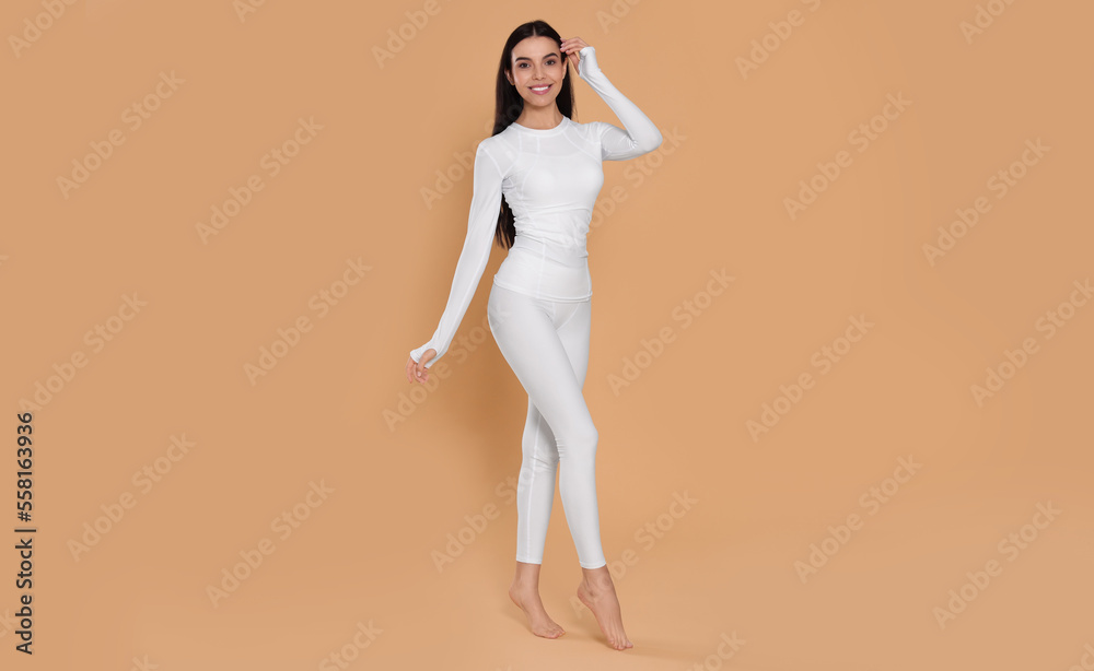 Woman in warm thermal underwear on beige background. Space for text Woman in warm thermal underwear on beige background. Space for text
