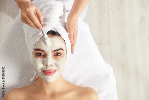 Cosmetologist applying mask on woman's face in spa salon, top view. Space for text