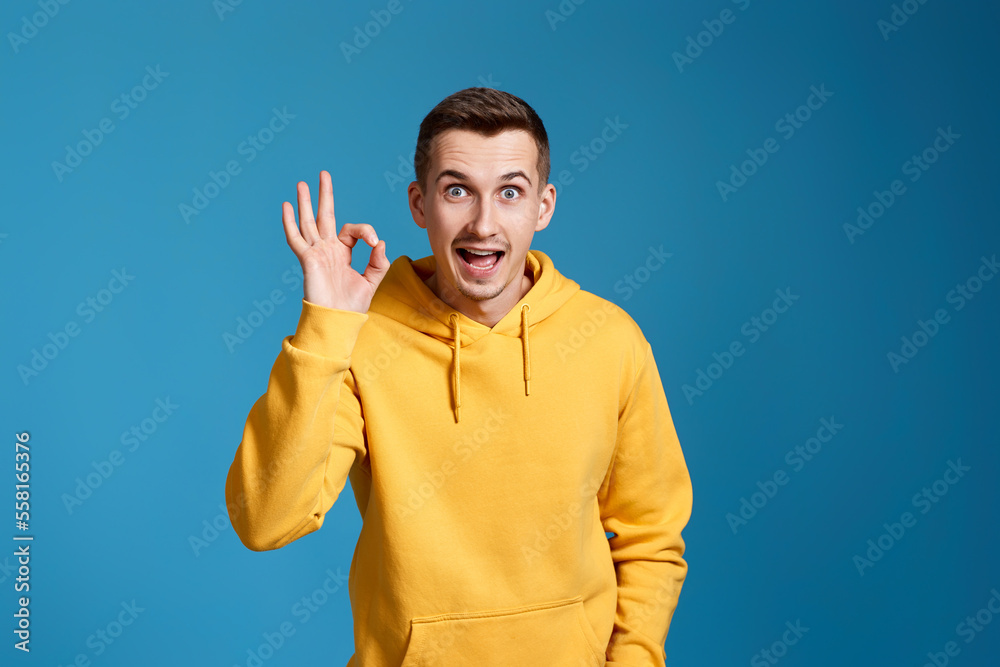young man in yellow sweatshirt showing Ok gesture young man in yellow sweatshirt showing Ok gesture