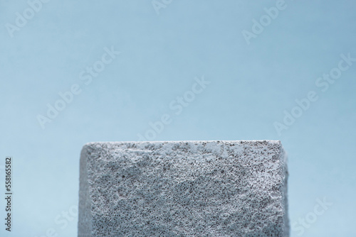Gray stone podium for cosmetics on a blue background.