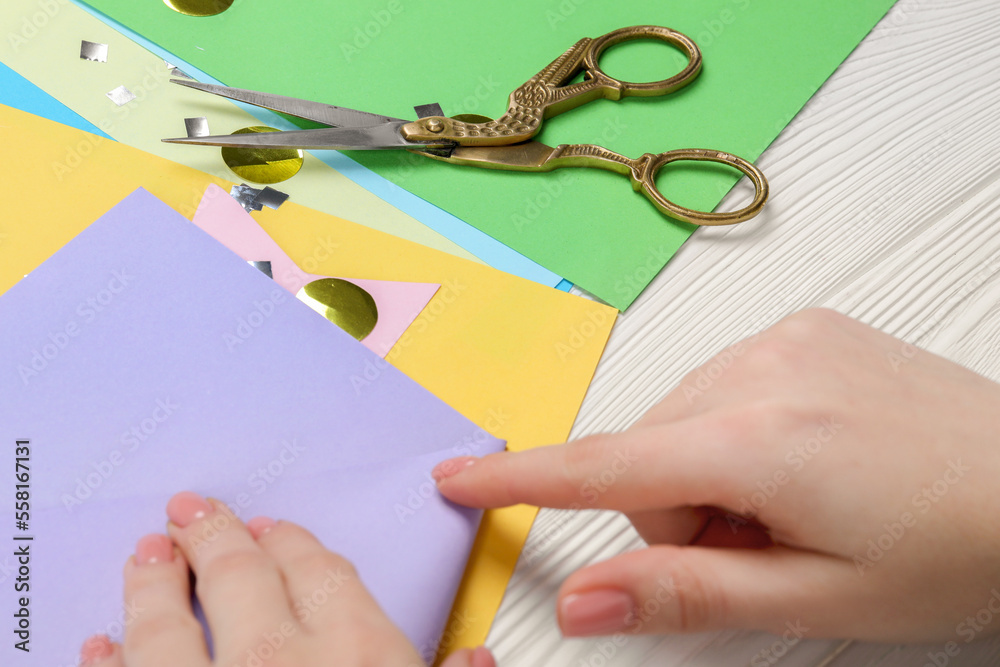 Woman with violet paper and scissors at white wooden table, closeup