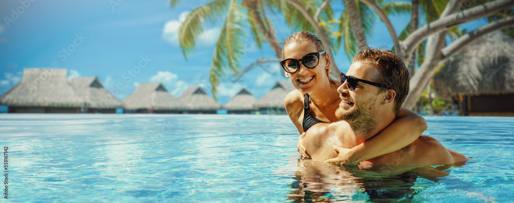 tropical resort summer vacation. happy couple relaxing in swimming pool with overwater bungalows in background. banner with copy space - obrazy, fototapety, plakaty 
