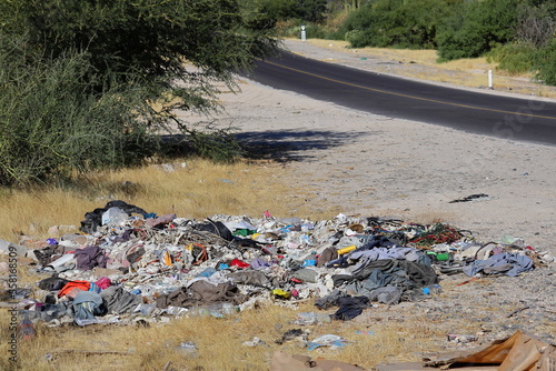 A pile of clothing trash, plastic and organic, thrown along the road