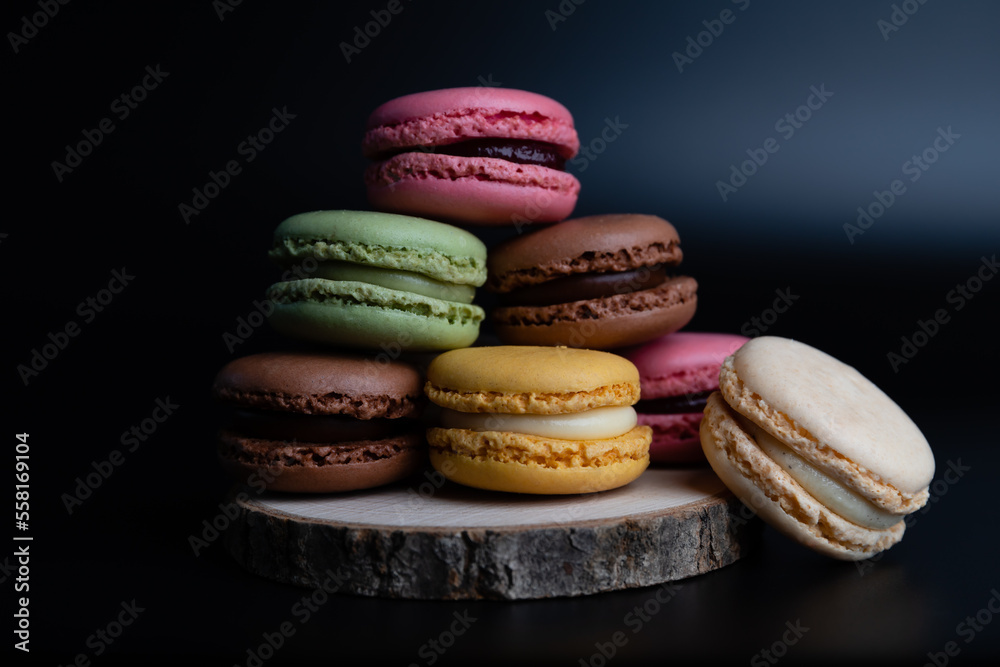 Macarons cookie dessert from France in a stack on wooden board and black background Macarons cookie dessert from France in a stack on wooden board and black background
