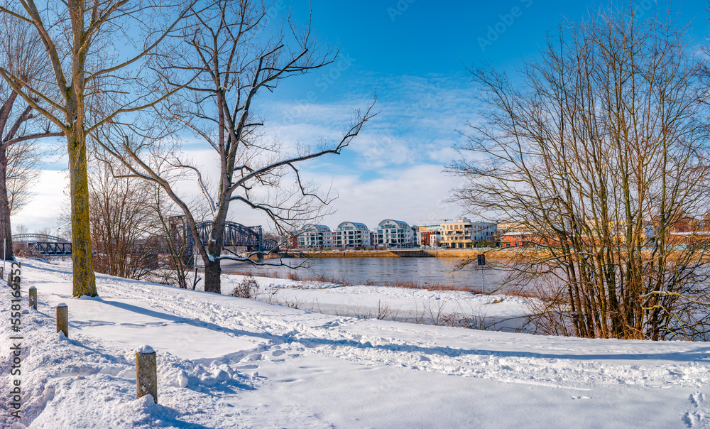 Panoramic view over Magdeburg historical downtown in Winter with icy trees and snow during sunrise in the morning with warm illumination and blue sky, Germany.