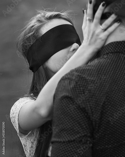 Romantic couple blindfolded with black ribbon touching each other. Love blind concept. Black and white