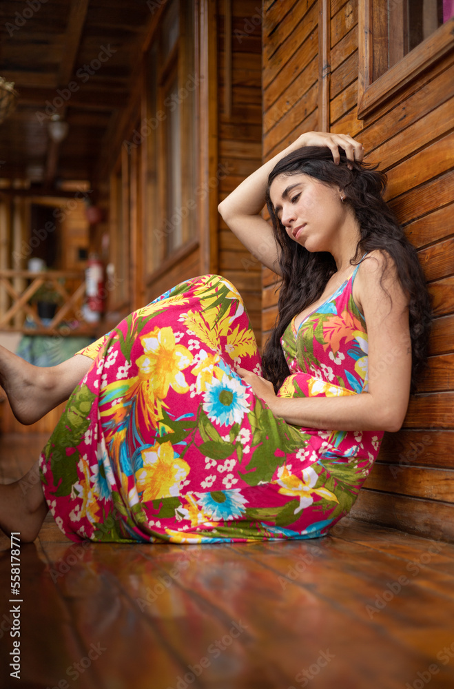 Fototapeta premium relaxed sitting young latin woman wearing colorful dress and with long hair, lifestyle and natural beauty, model portrait