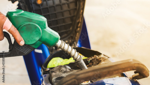 Green fuel dispenser refueling a motorcycle in a gas station. photo