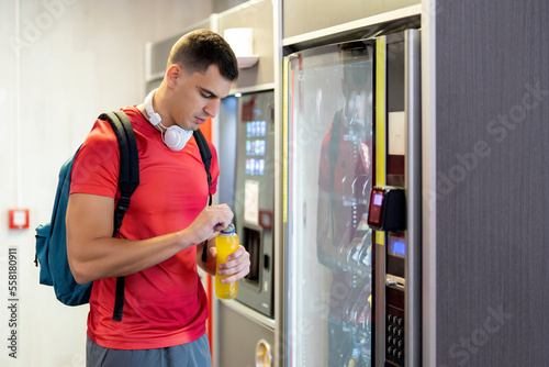 Athlete in gym consuming drink from food vending machine photo