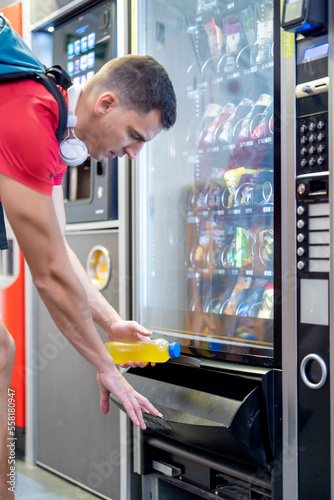 Athlete in gym consuming drink from food vending machine