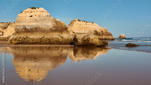 Beautiful limestone rocks reflect in the low tide ocean water. Praia dos Tres Castelos, Portugal
