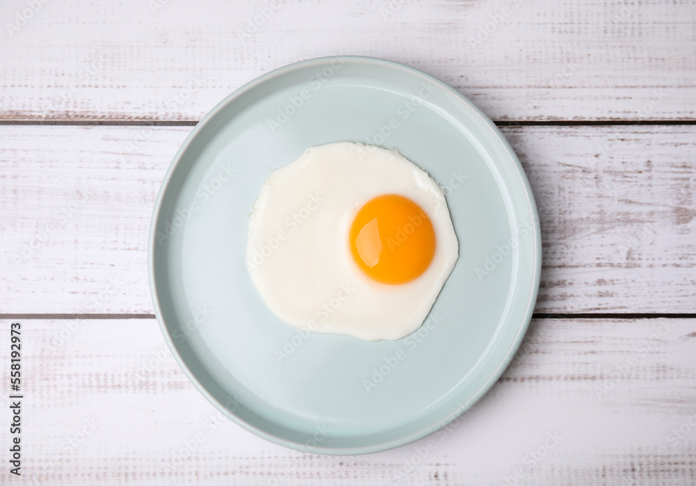 Tasty fried egg in plate on white wooden table, top view Tasty fried egg in plate on white wooden table, top view