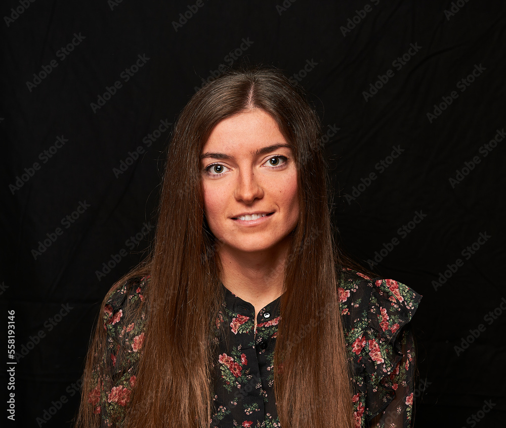 smiling girl in a black shirt with a flower print and long hair poses on a black cloth in the background smiling girl in a black shirt with a flower print and long hair poses on a black cloth in the background