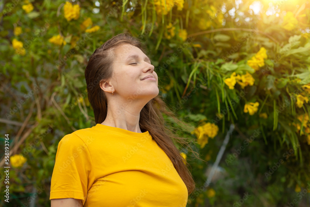 Portrait of happy beautiful bearded girl, young positive woman with beard is smelling beautiful yellow flowers in the garden, smiling, enjoying spring or summer day, breathing deep deeply fresh air Portrait of happy beautiful bearded girl, young positive woman with beard is smelling beautiful yellow flowers in the garden, smiling, enjoying spring or summer day, breathing deep deeply fresh air