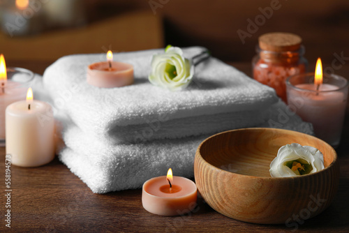 Beautiful spa composition with burning candles and flowers on wooden table