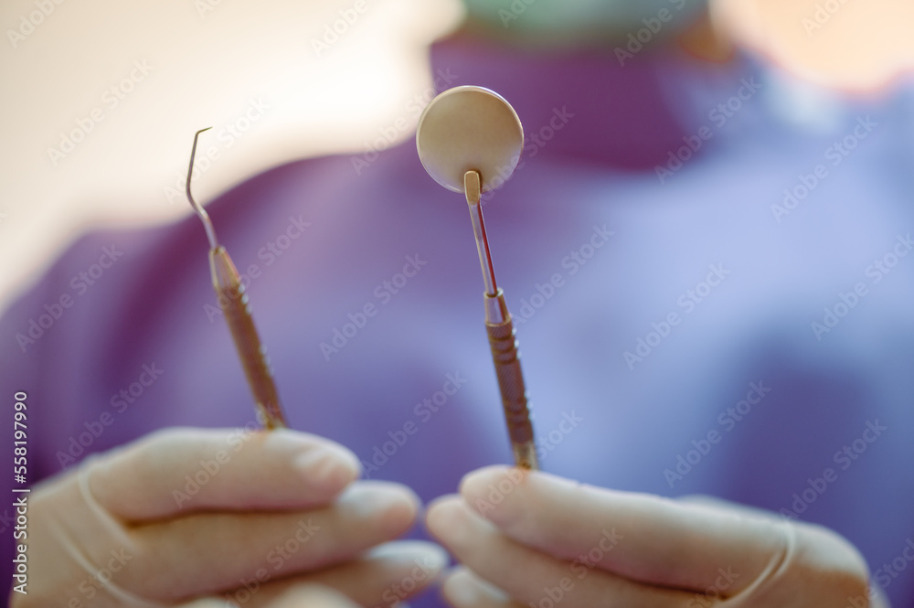 The dentist's hand holds the tooth checker and a mirror for checking and caring for the dentist's tools and equipment.