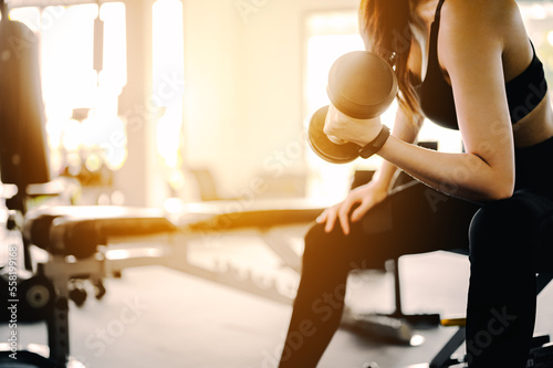 Fitness Asian Women in sportswear working out with weights over exercise bench exercising are lifting dumbbells at fitness gym in the morning.Fitness muscular body.Fitness, gym, workout and healthy.