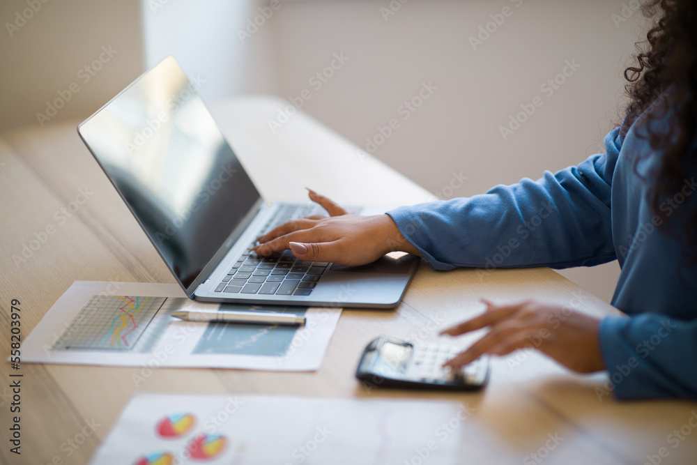 Close up focus on female hands making calculations on laptop Close up focus on female hands making calculations on laptop