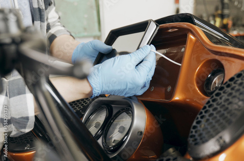 The mechanic installs a tablet on a motorcycle.