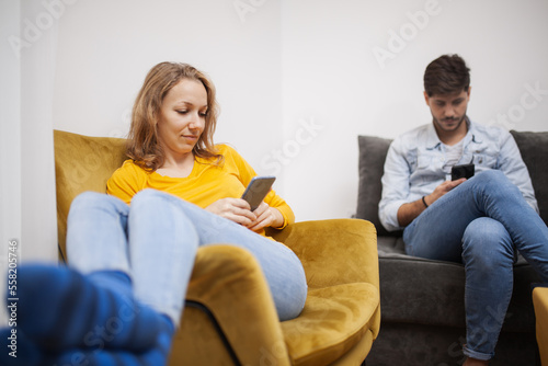 couple sitting at home livingroom looking at their smart phones