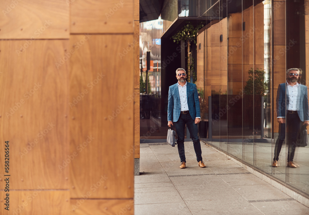 A senior businessman in a blue suit with a briefcase walking through the city