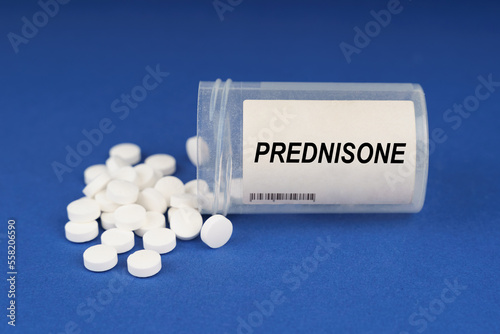 On a blue surface are pills and a dusty jar with the inscription - Prednisone photo