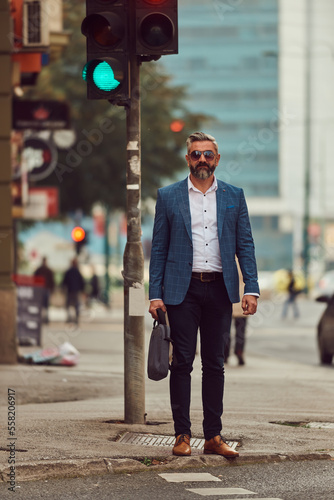 A senior businessman in a blue suit with a briefcase walking through the city