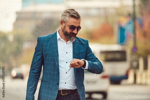 Fotografie business, punctuality and people concept - senior businessman checking time on w