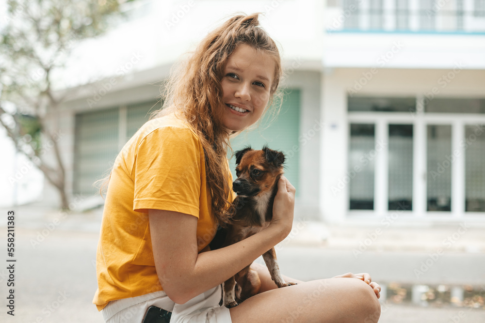Young girl picked up a homeless dog on the street, a person's hand strokes the dog, abandoned, frightened homeless puppy in a shelter for dogs Young girl picked up a homeless dog on the street, a person's hand strokes the dog, abandoned, frightened homeless puppy in a shelter for dogs