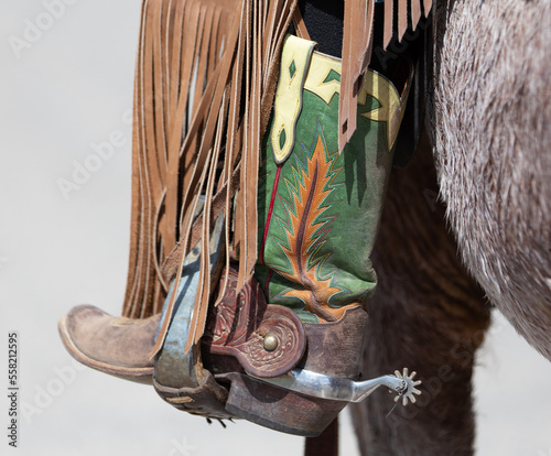 Green cowboy boot with spur in stirrup.