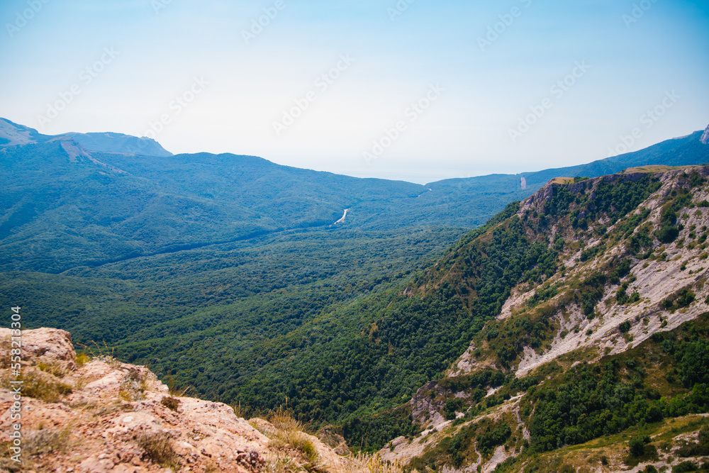 Mountain landscape in the warm season. Mountains and hills covered with forest, and blue sky. Beauty is in nature.
