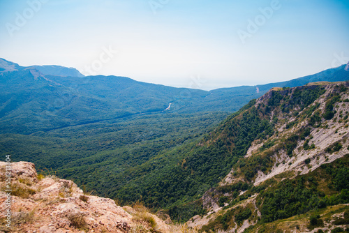 Mountain landscape in the warm season. Mountains and hills covered with forest, and blue sky. Beauty is in nature.