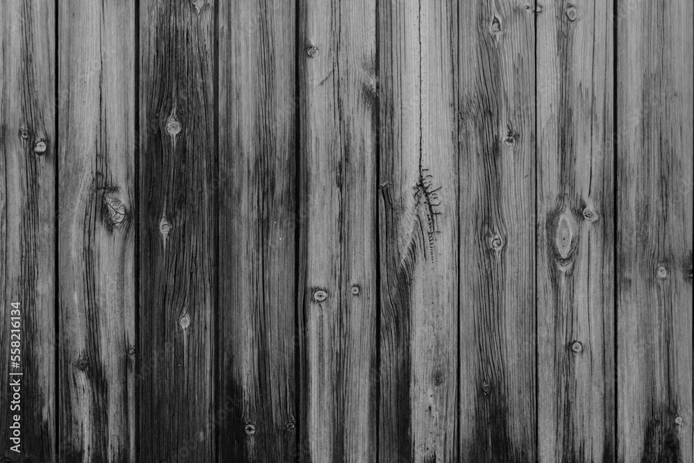 Naklejka premium Vertical black and white vintage weathered textured stained wood panel wall for background texture in any abstract scene