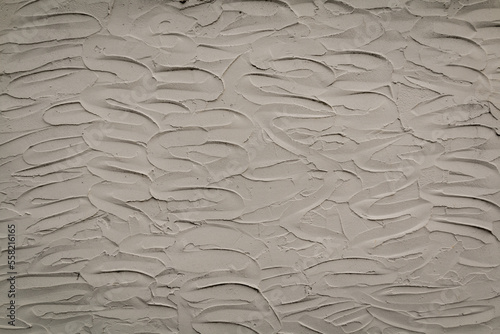 White wall or background of textured wavy stucco plaster material smeared onto surface creating a lovely design back and forth. Has shadows of black.