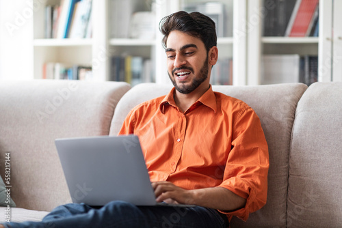 Happy arabic man freelancer working from home, using laptop
