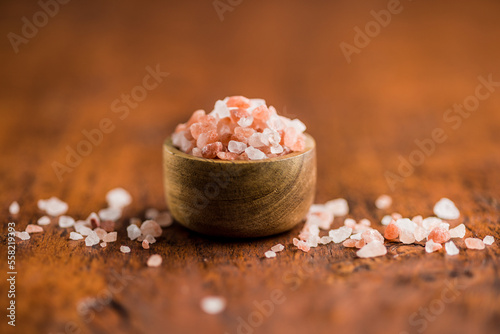 Pink himalayan salt in bowl on wooden table.