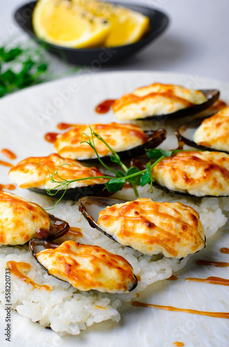 Baked mussels with cheese in shells on rice in a plate