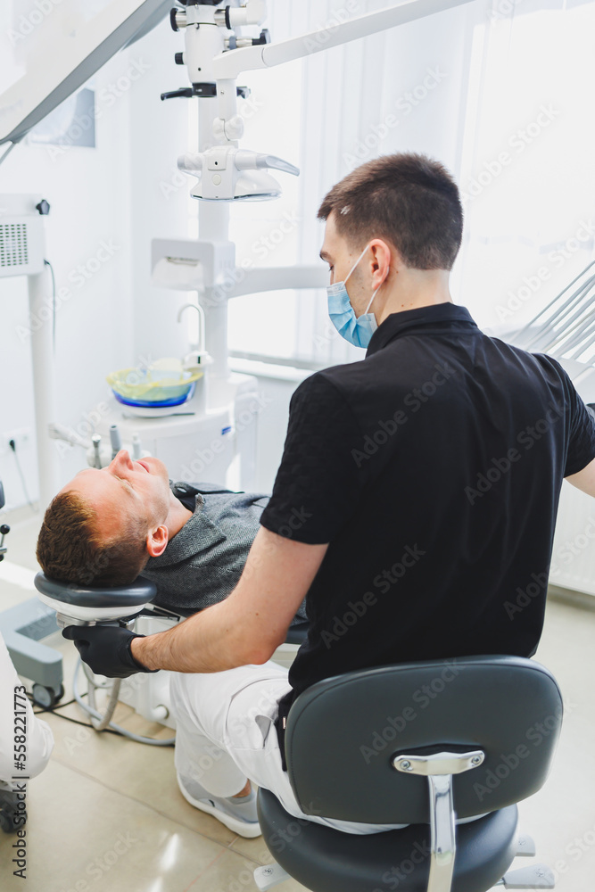 Fototapeta premium Dental office, examining a patient in a dental chair. Dental treatment is performed by a doctor and an assistant. Dental care.