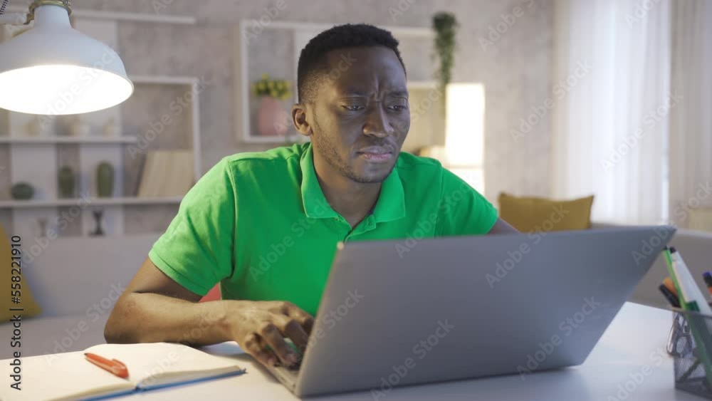 Thoughtful serious young african american businessman sitting at home office desk with laptop thinking solution ideas Thoughtful serious young african american businessman sitting at home office desk with laptop thinking solution ideas