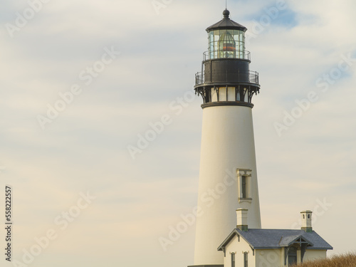 A beautiful white lighthouse against a cloudy sky. Close-up. Beautiful landscape. Majestic building. Navigation, romance, history, architecture.