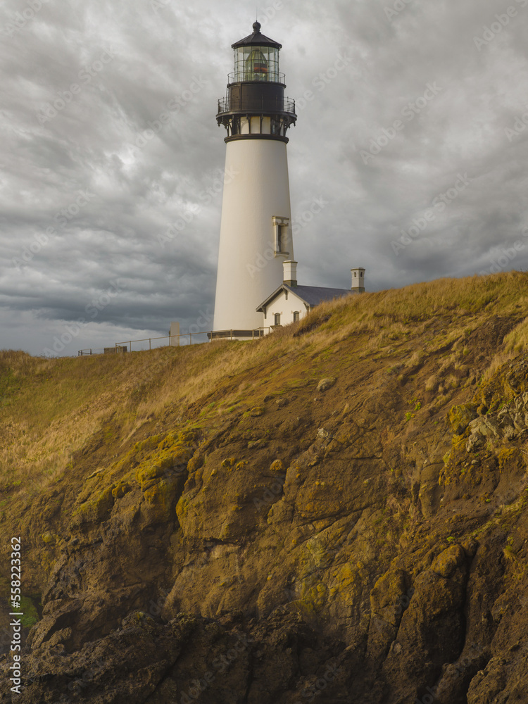 A beautiful white lighthouse under a gloomy sky with gray storm clouds. High rocky coast. Mystical landscape, weather, geology, excursions, tourism. A beautiful white lighthouse under a gloomy sky with gray storm clouds. High rocky coast. Mystical landscape, weather, geology, excursions, tourism.