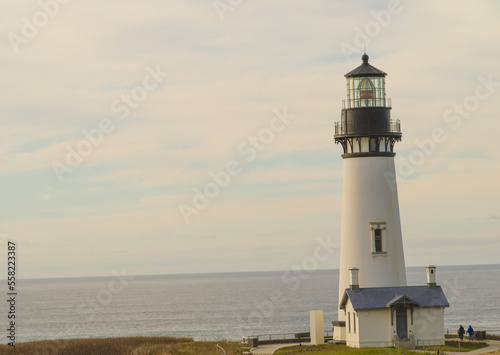 White beautiful lighthouse on the ocean. Blue sky with light white clouds. Beautiful seascape. Ecology, travel, travel destinations advertising, banner, postcard.