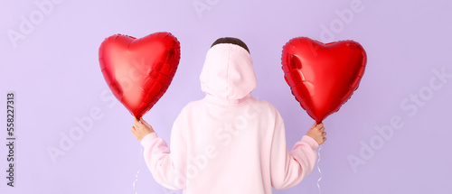 Woman with heart-shaped balloons for Valentine's Day on lilac background