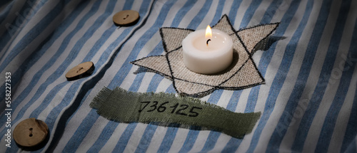 David star and burning candle on prisoner robe. International Holocaust Remembrance Day photo