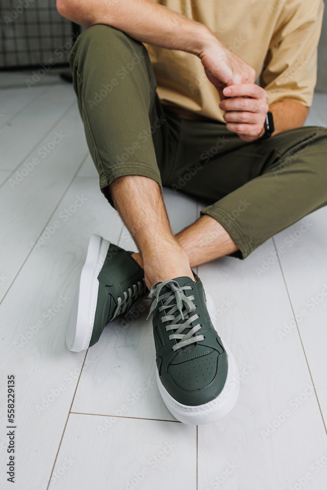 Male legs in pants and green casual sneakers. Men's fashionable shoes Male legs in pants and green casual sneakers. Men's fashionable shoes